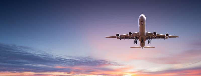 Année 2020 montrant un avion prenant son envol en décollant de la piste d’un aéroport devant un coucher de soleil